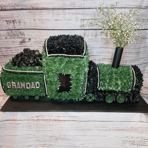 3D funeral tribute shaped like a steam train with coal carriage, crafted in green and black flowers