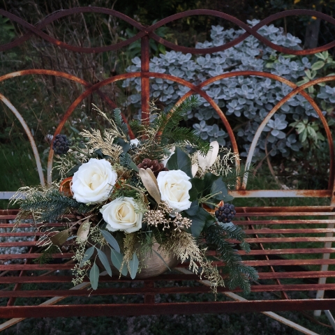 The Gilded Rose arrangement with white roses, gold eucalyptus, fresh pine, conifer, and ivy berry in a brushed gold bowl