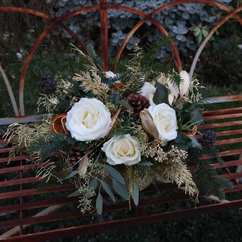 The Gilded Rose arrangement with white roses, gold eucalyptus, fresh pine, conifer, and ivy berry in a brushed gold bowl