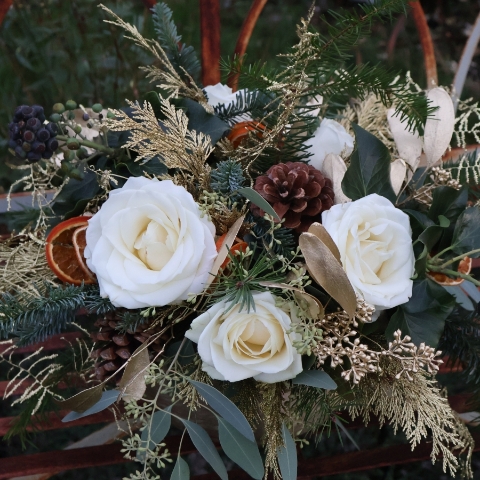 The Gilded Rose arrangement with white roses, gold eucalyptus, fresh pine, conifer, and ivy berry in a brushed gold bowl
