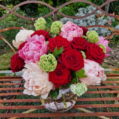 Spring vase of coral peonies and velvet red roses