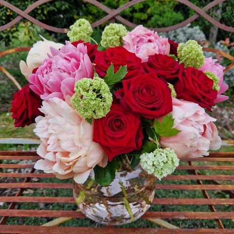 Spring vase of coral peonies and velvet red roses