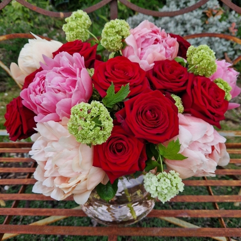 Spring vase of coral peonies and velvet red roses