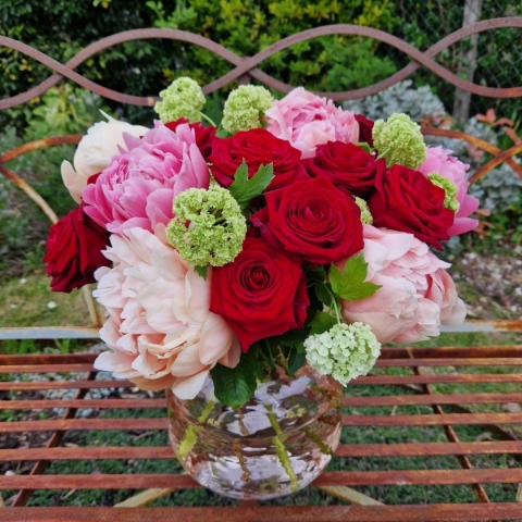 Spring vase of coral peonies and velvet red roses