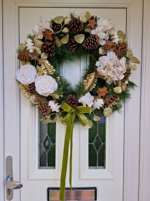 White faux flower Christmas wreath with roses, hydrangeas, gold accents, coco stars, pine cones, and velvet bow on a 50cm faux pine ring